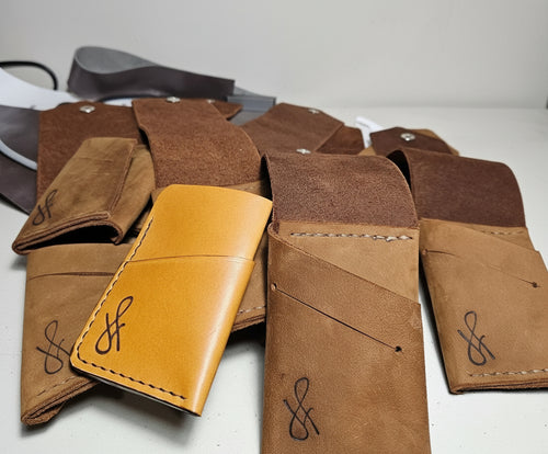 Collection of brown leather wallets with a brand logo on a white surface.