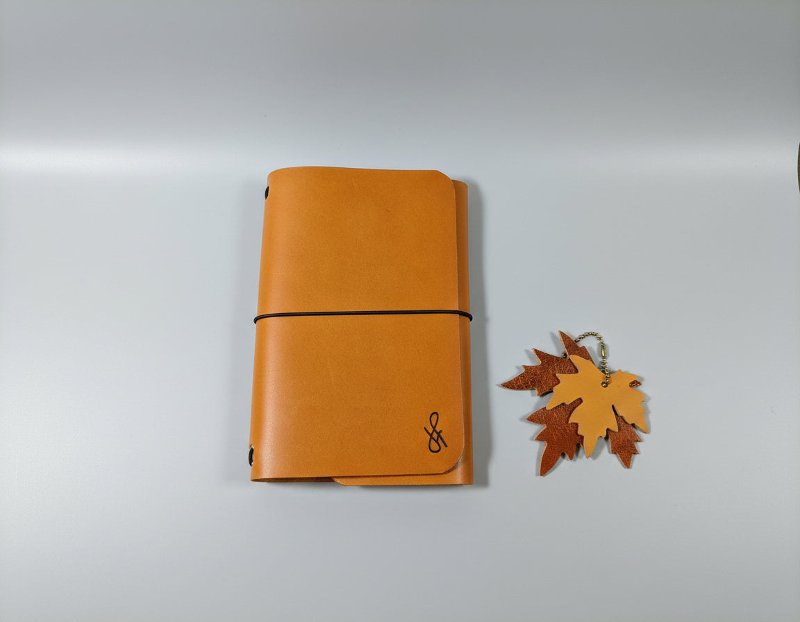 Tan leather notebook with a brand logo on a black surface