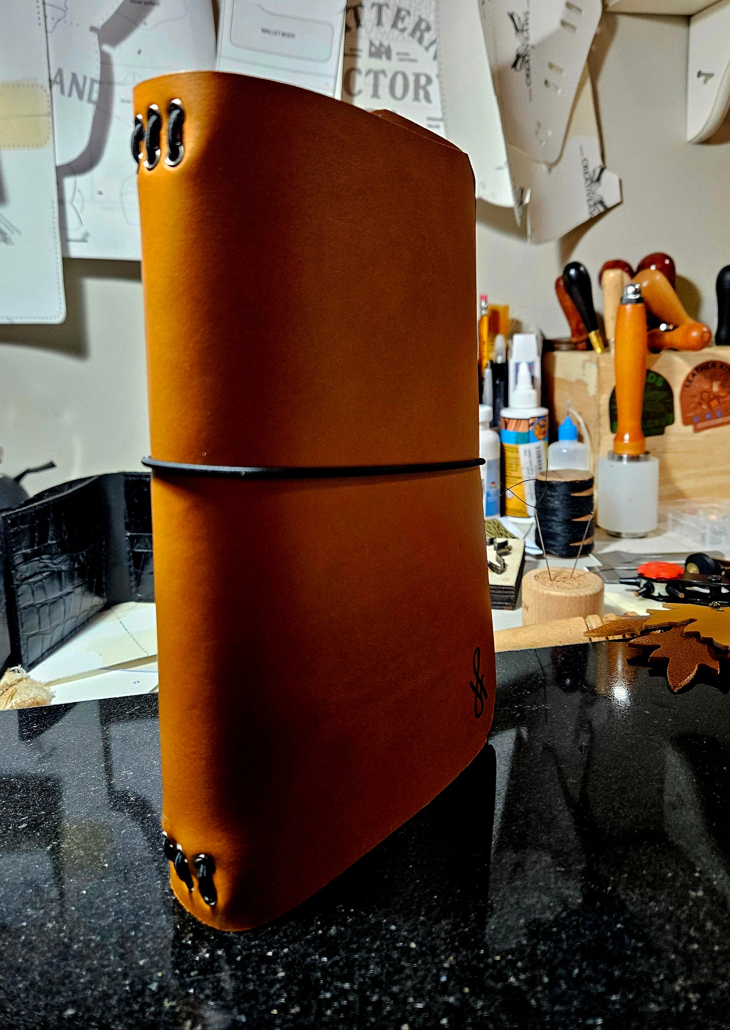 Brown leather notebook on a reflective surface with a workshop background