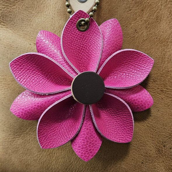 Brown leather bag with a pink flower accessory on a textured surface