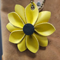 Yellow flower-shaped keychain attached to a brown leather bag.