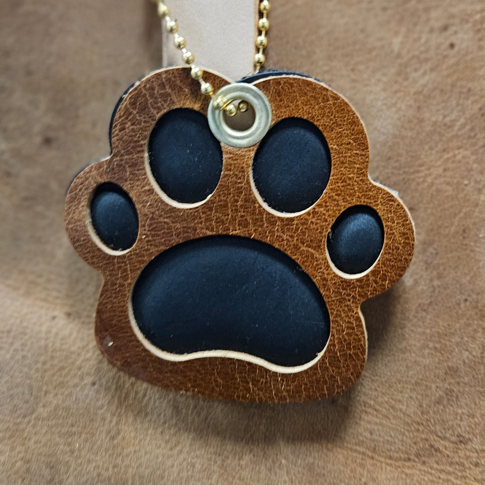 Leather paw print keychain on a beige background