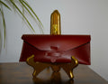 Red leather case on a gold stand with a blurred plant in the background