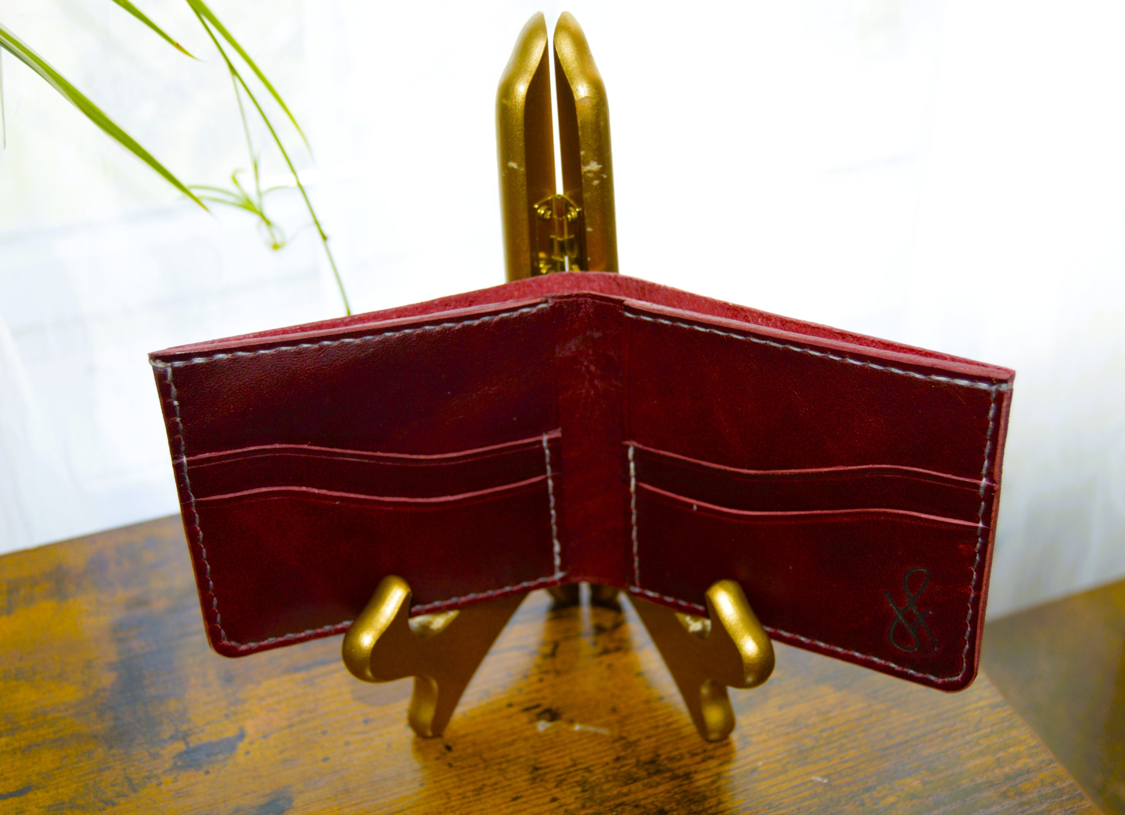 Red leather wallet on a gold stand with a white background